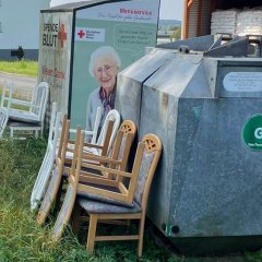 Abgestellte Stühle hinter Glascontainer